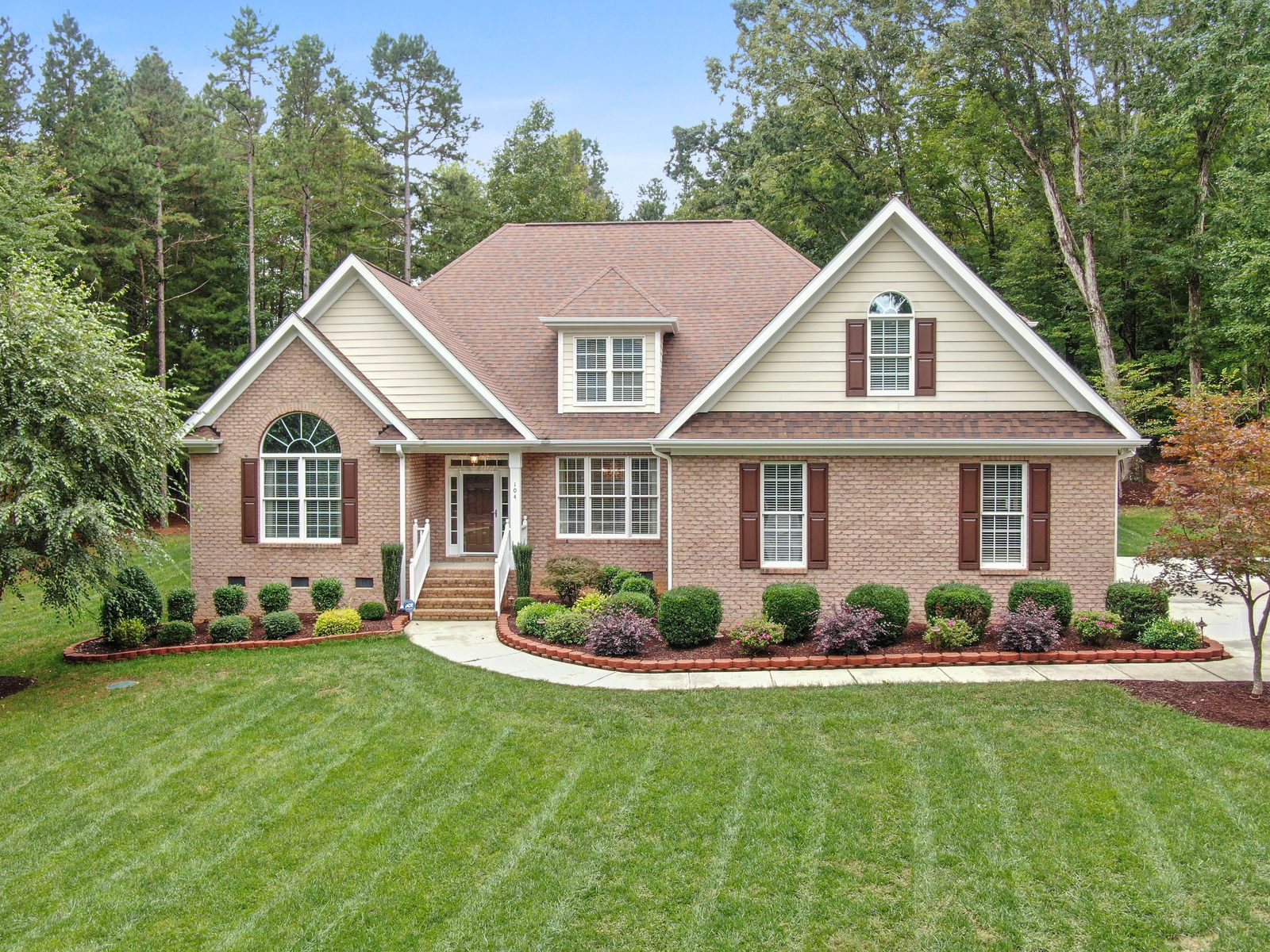 A brick ranch house with a green front lawn