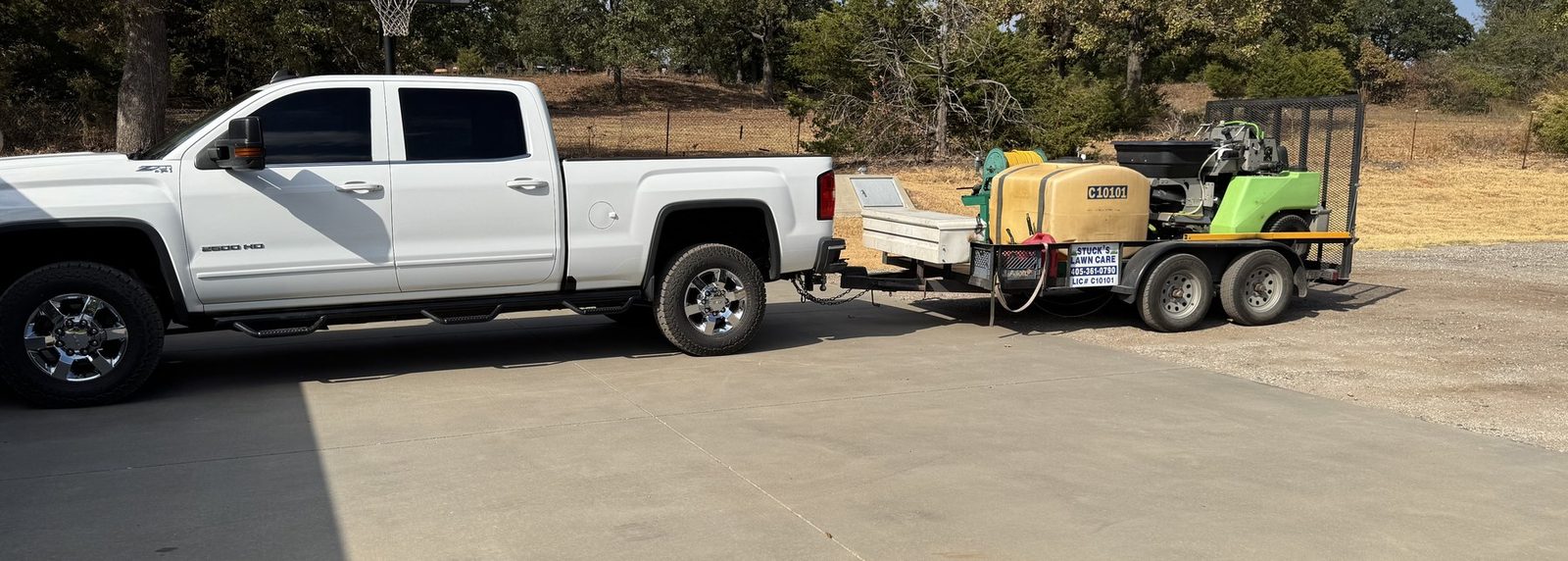 White pickup truck towing a green trailer on a residential street